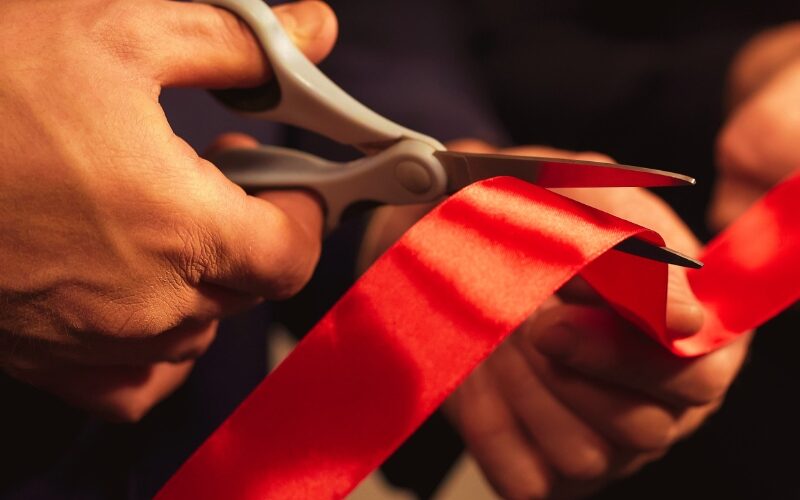 Business people hands cutting red ribbon close-up, new project, opening ceremony