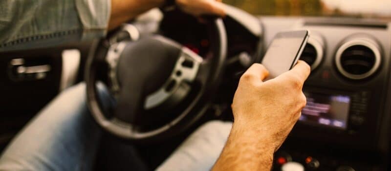 Young man in the car using his phone while driving