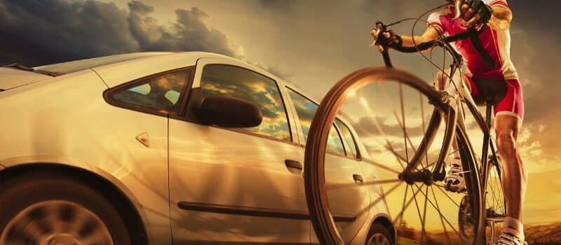 Speeding car passing beside cyclist on the road