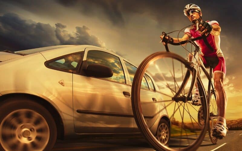 Speeding car passing beside cyclist on the road