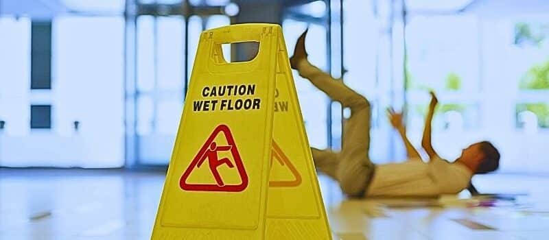 Businessman slipping on wet office floor. Causes of slip and fall accidents