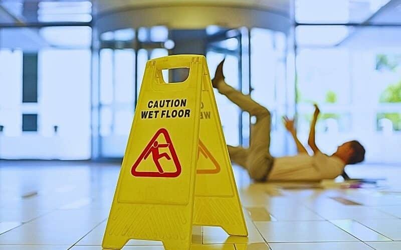 Businessman slipping on wet office floor. Causes of slip and fall accidents