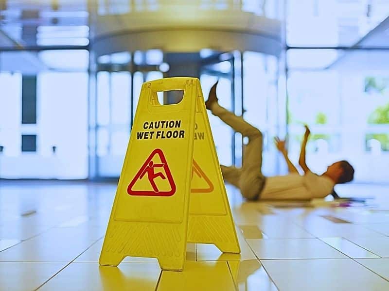 Businessman slipping on wet office floor. Causes of slip and fall accidents