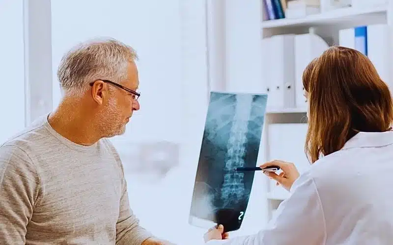 doctor with spine x-ray and senior man at hospital. spinal cord injury levels