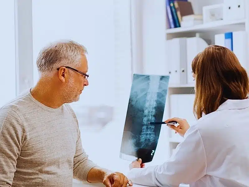 doctor with spine x-ray and senior man at hospital. spinal cord injury levels