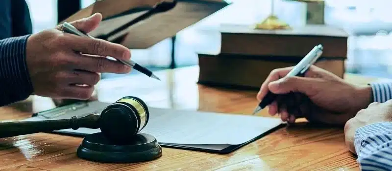 Man and lawyer discussing legal matters and signing contract papers.