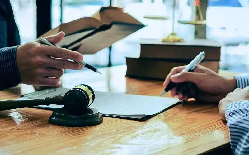 Man and lawyer discussing legal matters and signing contract papers.