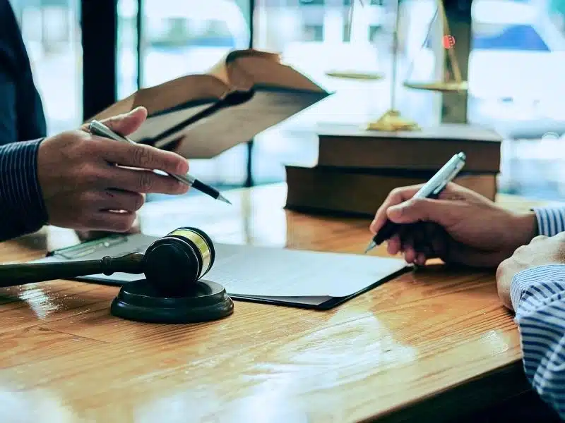Man and lawyer discussing legal matters and signing contract papers.