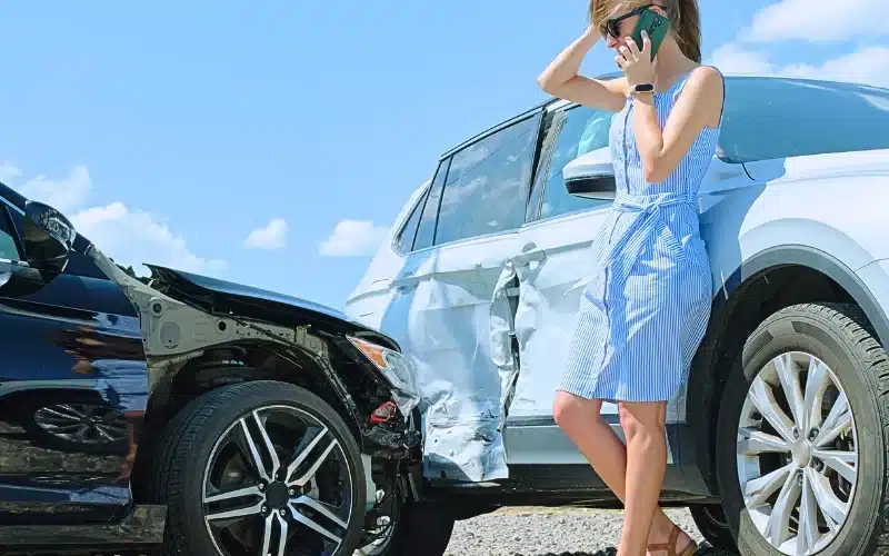 A frustrated woman using her mobile phone after a car crash.