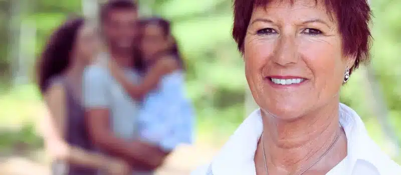 Smiling grandmother with her family at her back.
