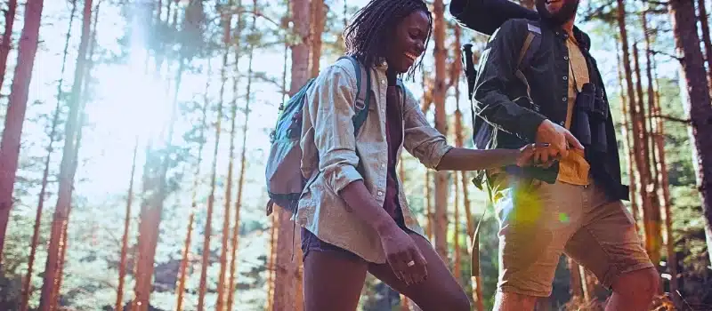 Happy couple hiking while holding hands.