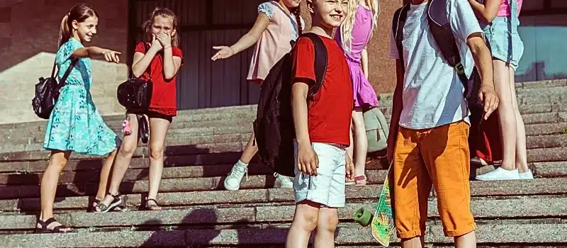 Happy kids playing at city's street in sunny summer's day in front of modern building.