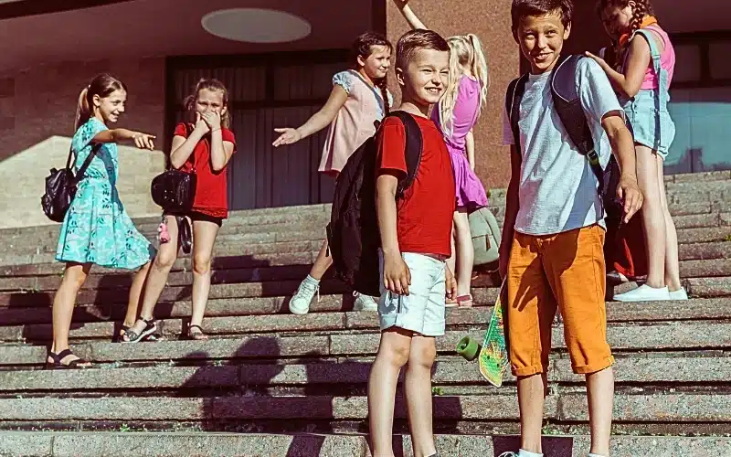 Happy kids playing at city's street in sunny summer's day in front of modern building.
