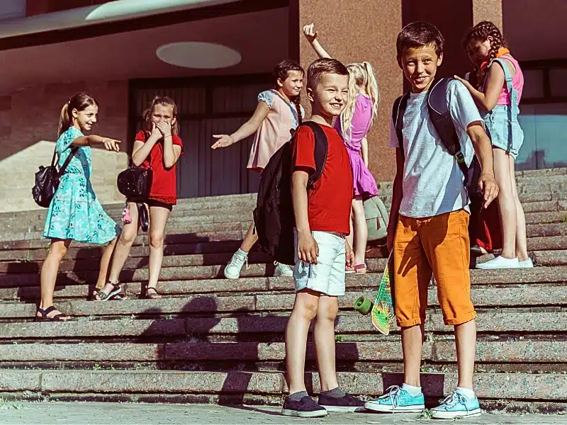 Happy kids playing at city's street in sunny summer's day in front of modern building.