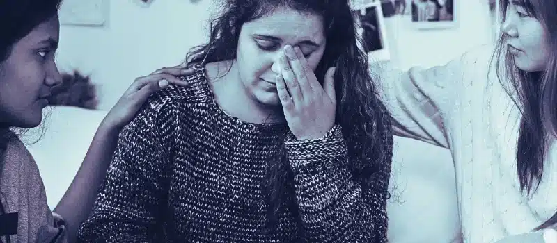 Teenage girls consoling their depressed crying troubled friend