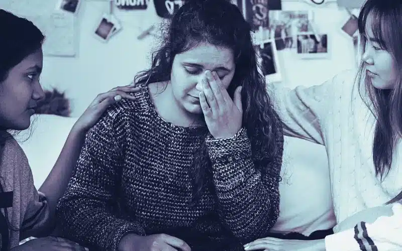 Teenage girls consoling their depressed crying troubled friend