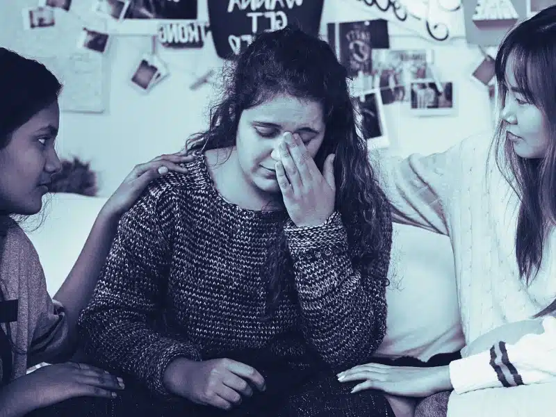 Teenage girls consoling their depressed crying troubled friend
