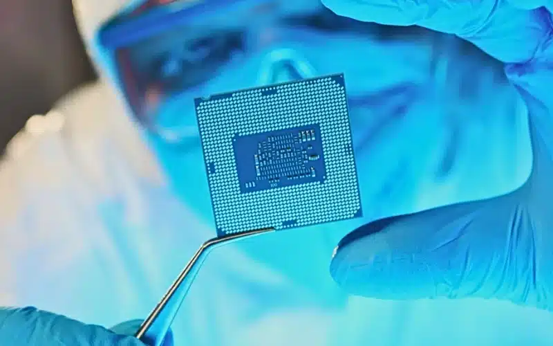 Scientist developer in protective suit holds microcircuit.