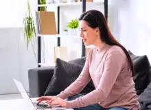 Woman working on a laptop in a comfortable, home-like setting.